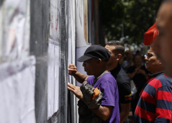 AME5617. CARACAS (VENEZUELA), 28/07/2024.- Ciudadanos venezolanos buscan su mesa de votación durante la jornada de elecciones presidenciales de Venezuela este domingo, en Caracas (Venezuela). El CNE informó este domingo que, sobre las 08.00 hora local (12.00 GMT), el 95 % de los 15.797 centros de votación ya estaban abiertos -dos horas más tarde la hora oficial fijada para la apertura- y computando los votos de personas que acudieron desde muy temprano a las urnas. EFE/ Henry Chirinos