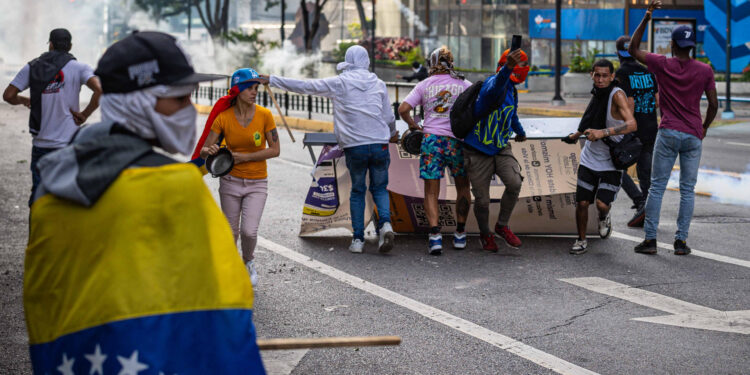 AME6327. CARACAS (VENEZUELA), 29/07/2024.- Manifestantes se enfrentan a la Guardia Nacional Bolivariana (GNB), por los resultados de las elecciones presidenciales este lunes, en Caracas (Venezuela). Este lunes, miles de ciudadanos han salido para protestar contra los resultados anunciados por el Consejo Nacional Electoral (CNE), que otorga al presidente Maduro el 51,2 % de los votos, un dato cuestionado por la oposición y por buena parte de la comunidad internacional. EFE/ Henry Chirinos