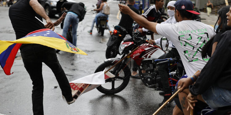 AME6288. CARACAS (VENEZUELA), 29/07/2024.- Una persona pstea un cartel con la imagen del presidente de Venezuela, Nicolás Maduro, durante una protesta por los resultados de las elecciones presidenciales este lunes, en Caracas (Venezuela). Protestas en Caracas luego de que el Consejo Nacional Electoral (CNE) proclamara a Nicolás Maduro como presidente reelecto de Venezuela, tras los comicios celebrados este 28 de julio. EFE/ Henry Chirinos