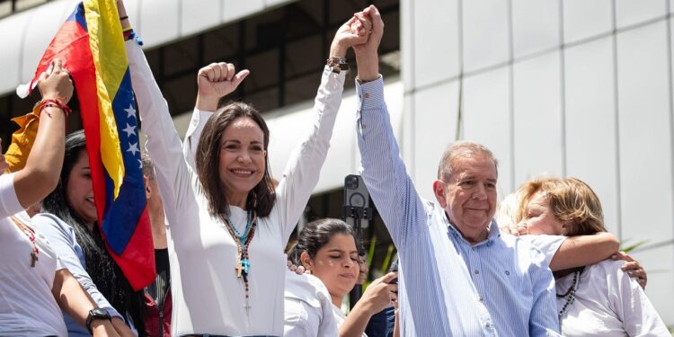 AME6560. CARACAS (VENEZUELA), 30/07/2024.- La líder opositora venezolana María Corina Machado (i) y el candidato a la presidencia de Venezuela Edmundo González Urrutia saludan en una manifestación de apoyo este martes, en Caracas (Venezuela). Miles de venezolanos se han concentrado este martes en Caracas, en un acto convocado por la oposición mayoritaria, para rechazar por segundo día consecutivo lo que consideran es un fraude en los resultados oficiales del Consejo Nacional Electoral (CNE), que en la víspera proclamó a Nicolás Maduro como presidente reelecto con el 51,2 % de los votos. EFE/ Ronald Peña R.