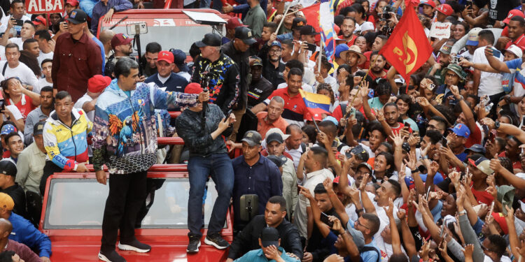 AME9271. CARACAS (VENEZUELA), 04/07/2024.- El presidente de Venezuela Nicolás Maduro (c) saluda a sus seguidores este jueves, en Caracas (Venezuela). El presidente de Venezuela, Nicolás Maduro, habló este jueves, en su primer acto de campaña para las elecciones del 28 de julio, de una "profecía" de pastores cristianos, según la cual el país ha entrado en un período de siete años de prosperidad, que acompañarán a quien gane los comicios. EFE/ Miguel Gutiérrez