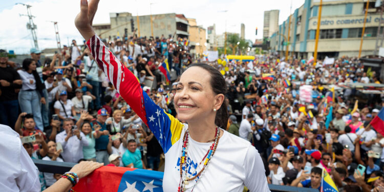 AME1670. VALENCIA (VENEZUELA), 13/07/2024.- La lider de la oposición, María Corina Machado (i) saluda a simpatizantes durante un acto de campaña este sábado en la ciudad de Valencia, estado de Carabobo (Venezuela). La líder opositora de Venezuela María Corina Machado sorteó este sábado "obstáculos" en su viaje hacia Valencia, estado Carabobo, al superar dos cierres de la autopista que conduce hacia esa ciudad, donde encabezará un acto de campaña junto al candidato presidencial Edmundo González Urrutia, de cara a las elecciones del 28 de julio. EFE/ Ronald Peña