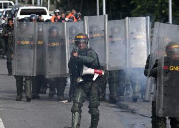 Members of the Bolivarian National Guard clash with opponents of Venezuelan President Nicolas Maduro's government during a protest at the El Valle neighborhood in Caracas on July 29, 2024, a day after the Venezuelan presidential election. - Protests erupted in parts of Caracas Monday against the re-election victory claimed by Venezuelan President Nicolas Maduro but disputed by the opposition and questioned internationally, AFP journalists observed. (Photo by Federico PARRA / AFP)