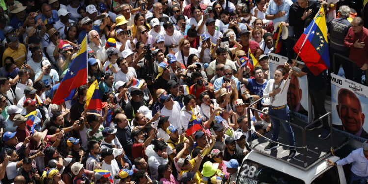 AME1189. CARACAS (VENEZUELA), 17/08/2024.- La líder de la oposición venezolana María Corina Machado (d) agita la bandera de Venezuela frente a seguidores este sábado, en Caracas (Venezuela). Machado reapareció en público para participar en la concentración contra el resultado oficial de las presidenciales que -asegura- ganó el abanderado de la mayor coalición opositora, Edmundo González Urrutia, pese a que el Consejo Nacional Electoral (CNE) otorgó el triunfo a Nicolás Maduro. EFE/ Miguel Gutiérrez