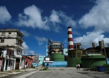 People walk past the Otto Parellada thermoelectric power plant in Havana on October 22, 2024. - Seventy percent of Cuba's population now has power, four days after a nationwide blackout triggered by the collapse of the island's largest power plant, and as the country recovers from Hurricane Oscar, the government said Tuesday. (Photo by YAMIL LAGE / AFP)