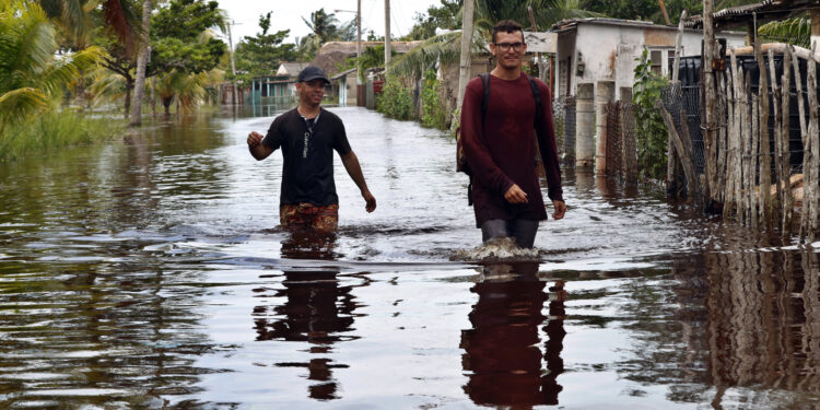 -FOTODELDÍA- AME2818. LA HABANA (CUBA), 26/09/2024.- Dos hombres caminan por una calle inundada de agua del mar este jueves, tras el paso del huracán Helen, en el poblado de Guanimar, en la costa sur de la provincia de Artemisa (Cuba). Intensas lluvias, algunas penetraciones del mar en zonas costeras bajas y fuertes vientos está dejando en el occidente de Cuba este jueves el paso del huracán Helene al oeste de la isla, con la previsión de que sus efectos se sigan sintiendo de forma decreciente durante esta jornada. EFE/ Ernesto Mastrascusa