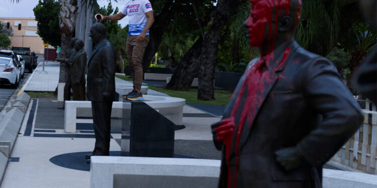 AME2750. SAN JUAN (PUERTO RICO), 29/10/2024.- Una persona derrama pintura en una estatua, este martes en San Juan (Puerto Rico). Tres activistas lanzaron pintura roja sobre las estatuas de presidentes estadounidenses del Paseo de los Presidentes, en la avenida de la Constitución, en el Capitolio de San Juan, como respuesta a los recientes insultos contra la isla caribeña. EFE/ Thais Llorca