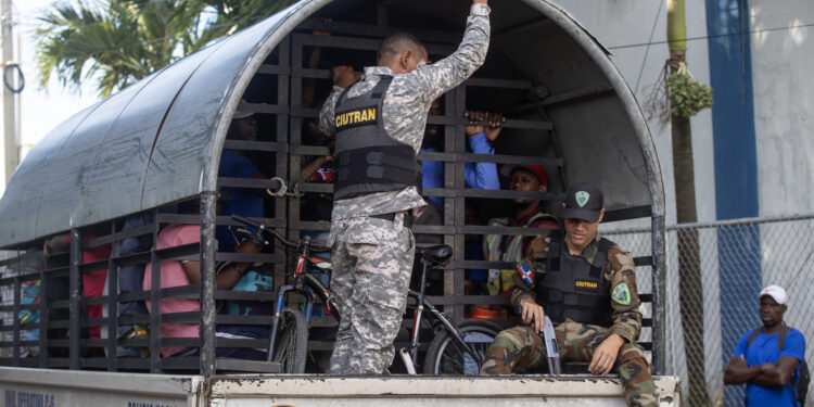 STO01.- HAINA (REPÚBLICA DOMINICANA), 07/10/2024.- Guardias vigilan a haitianos que fueron detenidos en redadas de autoridades migratorias, durante su traslado al centro de recepción de migrantes este lunes en Haina (República Dominicana). La decisión de la República Dominicana de deportar hasta a 10.000 indocumentados por semana mantiene en un estado de incertidumbre a los haitianos, que tratan de subsistir en la construcción, la agricultura o el comercio informal tras huir de su país, cuya situación económica y política se ha agravado en los últimos años por la violencia de las sangrientas bandas armadas. EFE/Orlando Barría