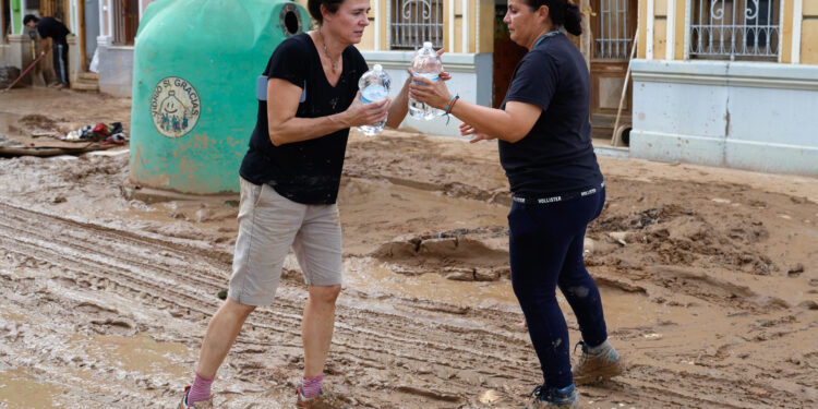 PICANYA (VALENCIA), 31/10/2024.- Una mujer entrega botellas de agua este jueves en Picanya (Valencia). La Comunitat Valenciana intenta recuperarse de la peor dana del siglo en España, que ha dejado más de un centenar de muertos en esa región, además de un inmenso escenario de daños en carreteras, calles e infraestructuras de numerosas localidades. EFE/Miguel Ángel Polo