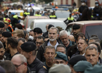 PAIPORTA (VALENCIA), 03/11/2024.- El rey Felipe (c), durante su visita a Paiporta este domingo. Gritos de 'fuera', así como lanzamiento de barro, están recibiendo a la comitiva de los reyes de España, el presidente del Gobierno, Pedro Sánchez, y el president de la Generalitat, Carlos Mazón, a su llegada al centro de Paiporta. Numerosas personas indignadas han recibido con insultos a la comitiva y se han encarado con ella, mientras que tanto el rey como la reina ha intentado mediar con jóvenes que se les han acercado. EFE/ Biel Aliño