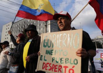 A man holds a sign against the government as he takes part in a march to commemorate the historic workers massacre of 1922 in Quito on November 15, 2024. On November 15, 1922, the government of Ecuador called on the military to suppress the Guayaquil general strike. (Photo by Galo Paguay / AFP)