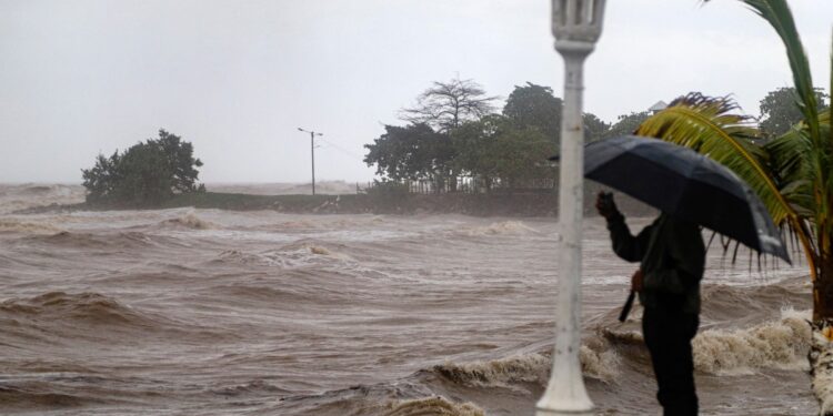 A person takes photos at the boardwalk during the passage of tropical storm Sara in La Ceiba, Honduras, on November 15, 2024. - Honduras' President Xiomara Castro said emergency services had been activated to deal with "damage already caused by the rains," warning that Sara's impacts "could become a catastrophic event." (Photo by ESAU OCAMPO / AFP)