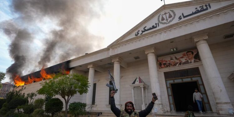 Combatientes de la oposición celebran mientras queman un tribunal militar en Damasco, Siria.