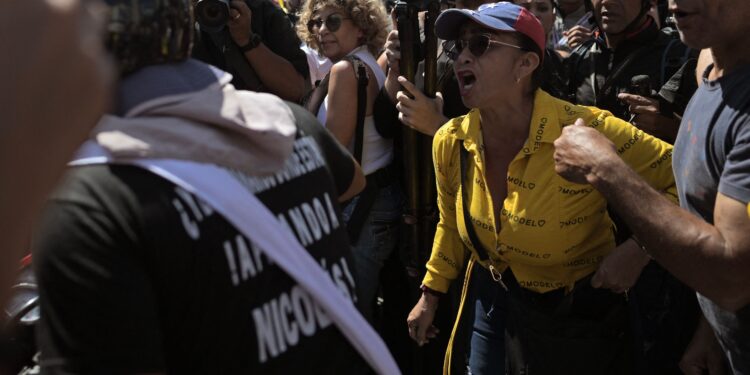 An opponet (C) of the Venezuelan government shouts at a supporter (L) of President Nicolas Maduro riding on a bike during a protest called by the opposition on the eve of the presidential inauguration, in Caracas on January 9, 2025. Venezuela is on tenterhooks facing demonstrations called by both the opposition and government supporters a day before President Nicolas Maduro is due to be sworn in for a third consecutive term and despite multiple countries recognizing opposition rival Edmundo Gonzalez Urrutia as the legitimate president-elect following elections past July. (Photo by JUAN BARRETO / AFP)