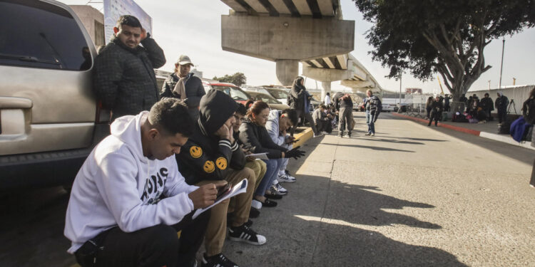 MEX333. TIJUANA (MÉXICO), 20/01/2025.- Migrantes permanecen varados este lunes, en el puerto fronterizo de El Chaparral, en Tijuana (México). Cientos de migrantes quedaron varados después de que el gobierno del nuevo presidente, Donald Trump, cancelara el programa CBP-One, que permitía a migrantes solicitar citas para pedir asilo en EE.UU. a través de los puertos de entrada en la frontera con México. EFE/ Joebeth Terríquez