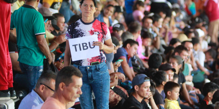 -FOTODELDÍA- AME2505. CÚCUTA (COLOMBIA), 19/01/2025.- Una mujer desplazada por la violencia sostiene un cartel en el estadio General Santander este domingo, en Cúcuta (Colombia). La ciudad de Cúcuta, limítrofe con Venezuela, se ha convertido en un símbolo del sufrimiento humano causado por el conflicto armado en la región del Catatumbo y es el lugar donde en los últimos días han llegado centenares de personas huyendo de la violencia desatada entre la guerrilla del Ejército de Liberación Nacional (ELN) y una disidencia de las FARC. EFE/ Mario Caicedo