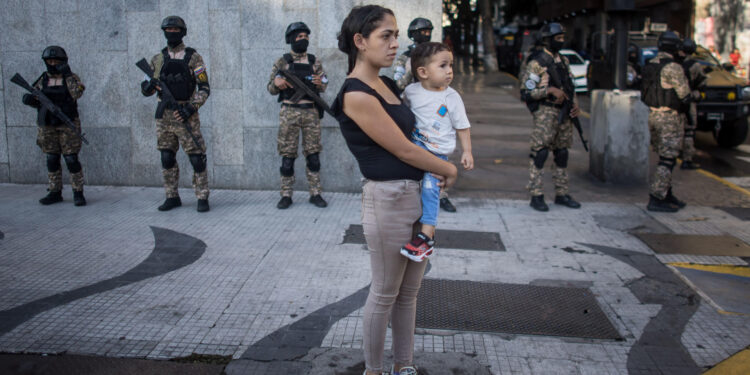 AME8642. CARACAS (VENEZUELA), 04/01/2025.- Una mujer observa un desfile de las "grandes marchas" en respaldo del presidente de Venezuela, Nicolás Maduro, este sábado en Caracas (Venezuela). Autoridades de Venezuela se reunieron este sábado para afinar los preparativos de cara al 10 de enero, cuando Nicolás Maduro afirma que asumirá el nuevo mandato presidencial correspondiente al período 2025-2031 tras una cuestionada reelección que la mayor coalición opositora, Plataforma Unitaria Democrática (PUD), tacha de fraudulenta. EFE/ Miguel Gutiérrez