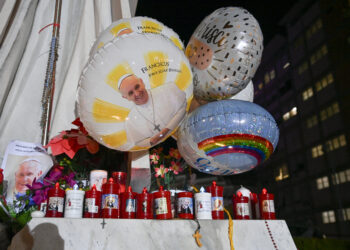 Balloons are attached at the statue of John Paul II where people bring candles and come to pray outside the Gemelli hospital where Pope Francis is hospitalized for pneumonia, in Rome on February 23, 2025. Pope Francis had a quiet night in hospital, the Vatican said on February 23, 2025, the morning after revealing the 88-year-old was in a "critical" condition. "The night passed peacefully, the pope rested," the Holy See said in a short update. (Photo by Isabella BONOTTO / AFP)