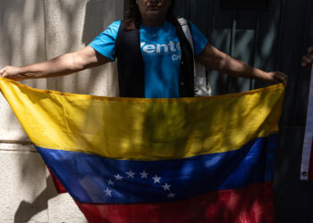 AME1640. SANTIAGO (CHILE), 20/02/2025.- Una mujer sostiene una bandera de Venezuela frente a la Nunciatura Apostólica este jueves, en Santiago (Chile). El Comando con Venezuela en Chile, representante de la disidencia venezolana en el país austral, entregó este jueves una carta a la Nunciatura Apostólica para pedir que la Iglesia católica "auxilie" a los cinco opositores del régimen chavista que llevan once meses en la embajada argentina en Caracas. EFE/ Ailen Díaz